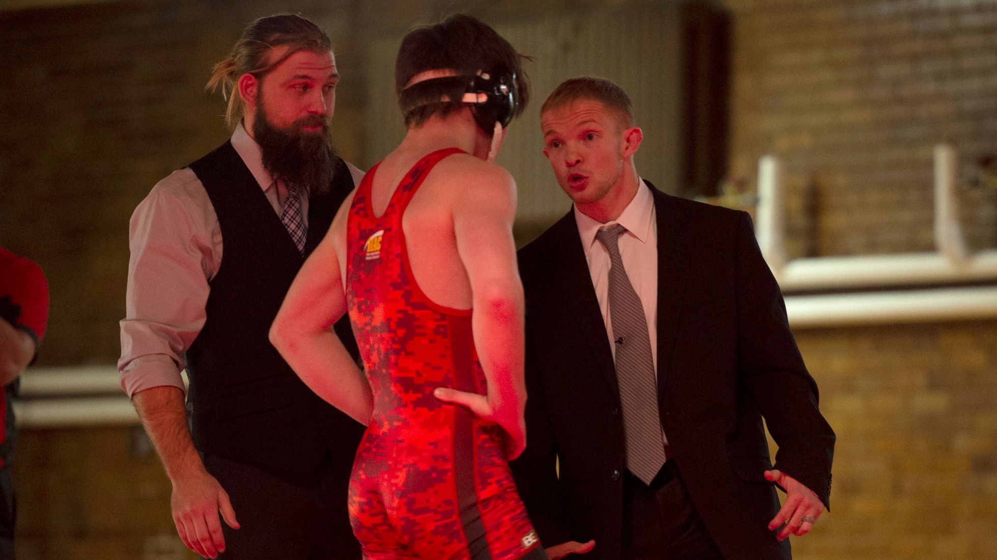 Assistant coach Gunnar Wolfensperger (L) and head coach Dylan Peters talk with Sam McCoy during the dual.